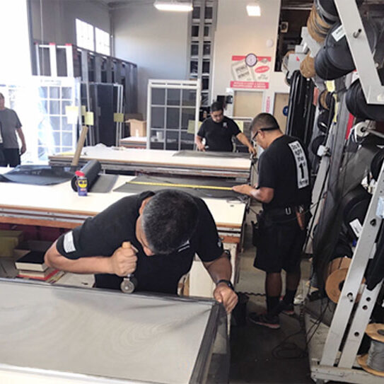 Workers assembling window screens in busy workshop