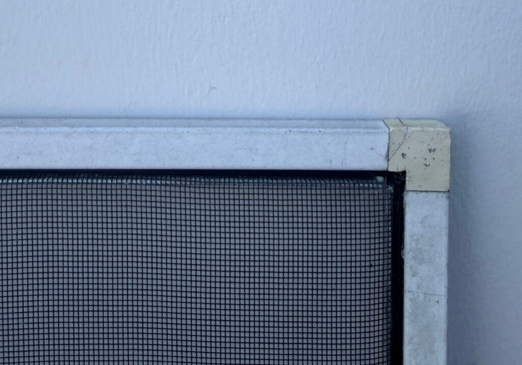 Corner of metal window screen against wall